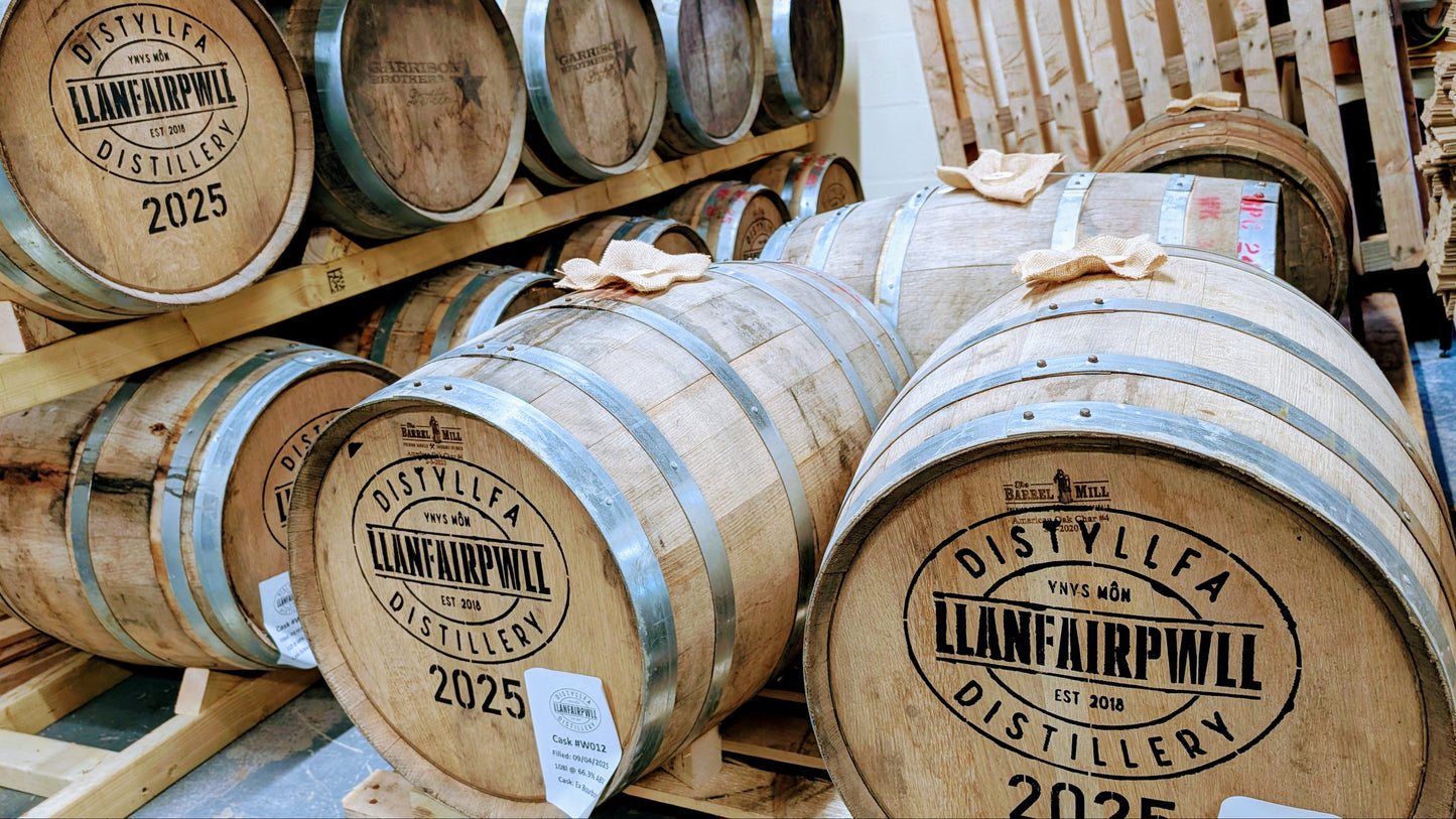 Wooden barrels with 'Distyllfa Llanfairpwll' branding stacked on a wooden pallet.